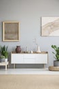 White cupboard between plants in grey living room interior with Royalty Free Stock Photo