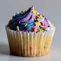 White cupcake with blue and purple frosting with confetti sprinkles, delicious baked good Royalty Free Stock Photo