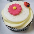 A white Cupcake with pink and yellow sugar flower