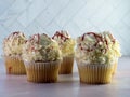 White cupcakes with white frosting swirled high and curled white chocolate with red raspberry drizzle over the top, delicious