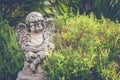 White cupid sculpture or statue place on outdoor garden surrounded with green natural for gardening decoration.