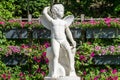 White Cupid statue in front of a pink flowerbed