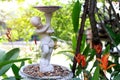 White cupid statue in a garden full of red flowers