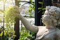 White cupid statue holding a bird on the hand in the green garden.Thailand. Royalty Free Stock Photo