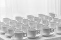 White cups for tea stacked in line on table with tablecloth for coffee-break. Royalty Free Stock Photo