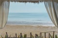 The white curtain on the top left and right edge of the white iron of the beach pavilion.