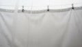 A white curtain is visible slightly out of focus with black hooks attached Royalty Free Stock Photo