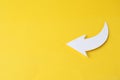 White curved paper arrow on yellow background, top view. Space for text
