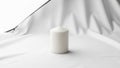 Cylindrical candle is placed on a smooth surface with a backdrop of gently Royalty Free Stock Photo