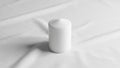 White cylindrical candle placed on a smooth white fabric surface Royalty Free Stock Photo