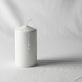 A white cylindrical candle is placed on a white fabric surface Royalty Free Stock Photo