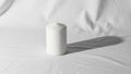Cylindrical candle stands on a crumpled white fabric background casting Royalty Free Stock Photo