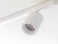 White cylindrical spotlight hanging from ceiling track lighting system Royalty Free Stock Photo