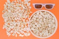 White 3d glasses paper cup and fresh cheesy popcorn on a orange background, top view, copyspace Royalty Free Stock Photo