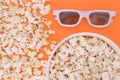 White 3d glasses, paper cup and fresh cheesy popcorn on a orange background, top view, copyspace Royalty Free Stock Photo