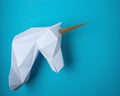 White 3d papercraft model of unicorn head on blue background. Minimal art concept