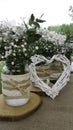 White daisy bouquet in glass jar and wattle white heart in green Royalty Free Stock Photo