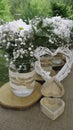 White daisy bouquets in glass jars, open wooden heart box and wattle white heart in the garden Royalty Free Stock Photo