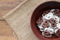 White and dark salted chocolate covered mini pretzels in a bowl on burlap texture on wood table. Homemade assorted mini pretzel