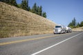 White day cab big rig semi truck transporting hazardous liquid cargo in two tank semi trailers running on the narrow road between Royalty Free Stock Photo