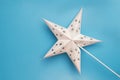 White decorated paper star on a light blue background; Christmas decoration Royalty Free Stock Photo