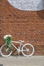 White decorative old bike with a basket of flowers against a brick wall. Copy space Royalty Free Stock Photo