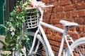 White decorative old bike with a basket of flowers against a brick wall. Copy space Royalty Free Stock Photo