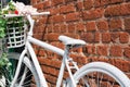 White decorative old bike with a basket of flowers against a brick wall Royalty Free Stock Photo