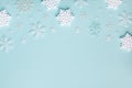 White decorative snowflakes on turquoise pastel background. Christmas or New year holiday card top view. Minimalistic flat lay