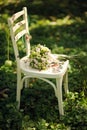 White decoupage chair with green bridal bouquet. Green grass at the apple garden, wedding ceremony. Summer wedding. Soft blur boke Royalty Free Stock Photo