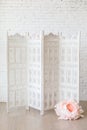 White delicate decorative wood panel with big paper flowers on white brick wall. Royalty Free Stock Photo