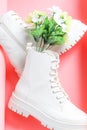 White demi-season martens boots with a bouquet of spring flowers on a pink .
