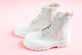 White demi-season martens boots made of eco-leather with a rough sole stand on a pink.