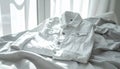 White denim jacket lying on rumpled white bed sheets in front of a window Royalty Free Stock Photo