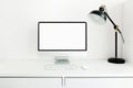 White desktop with blank white monitor and desk lamp. Workplace concept. Mock up blank computer screen with keyboard. Royalty Free Stock Photo