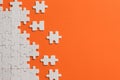 White details of puzzle on orange background Royalty Free Stock Photo