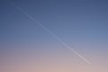 White diagonal aircraft trace on clear gradient evening sky after sunset. Plane trace.