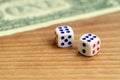 White dice are next to a dollar bill of US dollars on a wooden background. The concept of gambling with rates in monetary unit Royalty Free Stock Photo