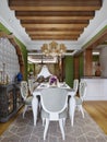 White dining table with green chairs against the wall with arabic stucco pattern and wood framing in an arabic style interior