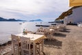 White dining tables on the sea shore with impressing sea view and Klima fishermen village in the background on Milos Island,Greece Royalty Free Stock Photo