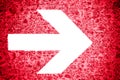 White directional arrow pointing towards right painted on a bright red grungy irregular wooden texture background