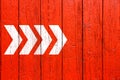 White directional arrow signs pointing direction painted on a red wood wall signboard texture background Royalty Free Stock Photo