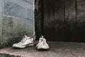 White dirty pair of sneakers with grunge old wood wall backgrou