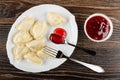 Dish with dumpling, spoon with jam, fork, bowl with strawberry jam on wooden table. Top view