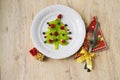 white dish with christmas tree made of kiwi, raspberries, cowberry and huckleberry on wooden table Royalty Free Stock Photo