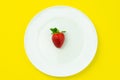 White dish with one strawberry on isolated yellow background.Creative minimal food concept with copy space Royalty Free Stock Photo