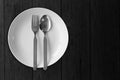 White dish plate with fork spoon on black wooden blank empty no food image for decoration Royalty Free Stock Photo