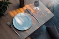 White dish plate on wooden table next to stylish utensils. 3d rendering.