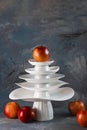 White dishes Pyramid like Christmas tree with red apples on top amd next to, on dark background. Creative concept, dishware, veg, Royalty Free Stock Photo