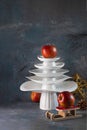 White dishes Pyramid like Christmas tree with red apples on top amd next to, on dark background. Creative concept Royalty Free Stock Photo